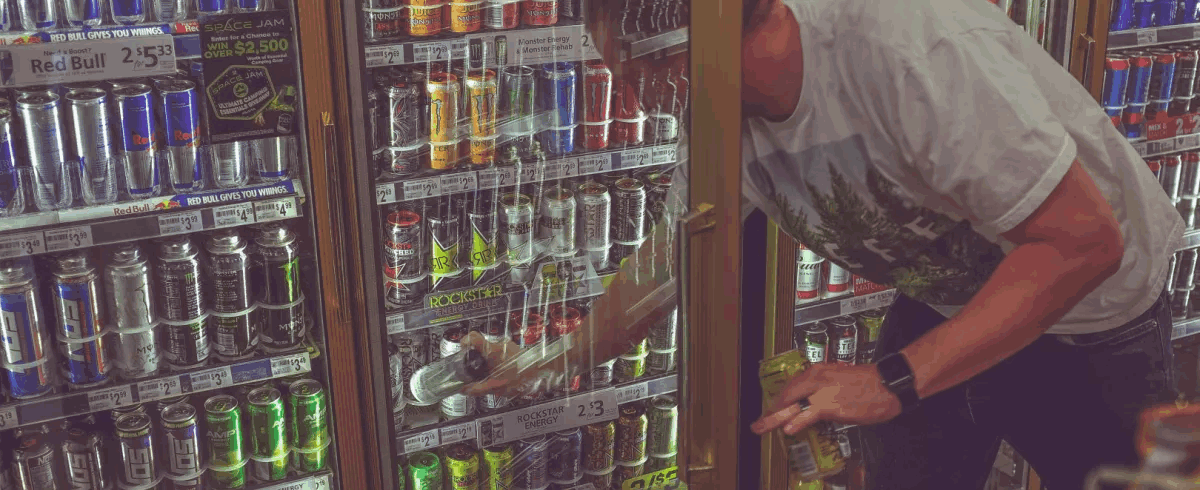 Man getting a beer from a market fridge image
